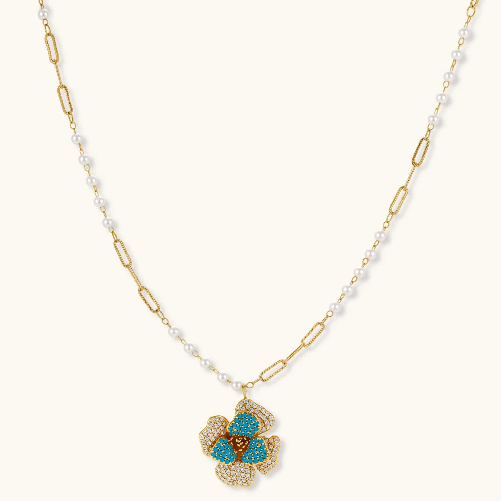 14K gold-plated floral jewelry set with blue cubic zirconia centers and pearl chain details on white background.