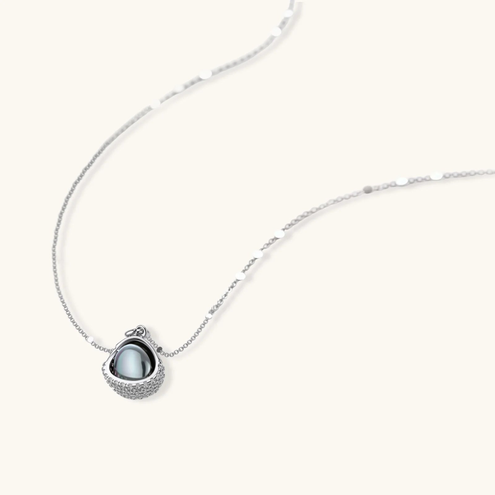 Elegant spherical pendant necklace and earrings set featuring crystal-pavé bottom half in gold or silver finish on white background.