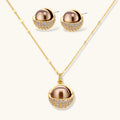 Elegant spherical pendant necklace and earrings set featuring crystal-pavé bottom half in gold or silver finish on white background.