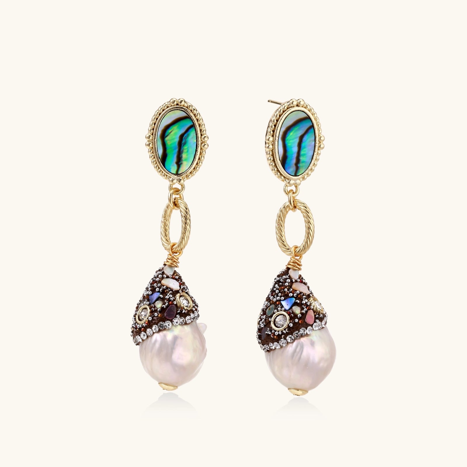 Gold drop earrings with iridescent abalone studs, rope links, jeweled caps and white baroque pearls on cream background
