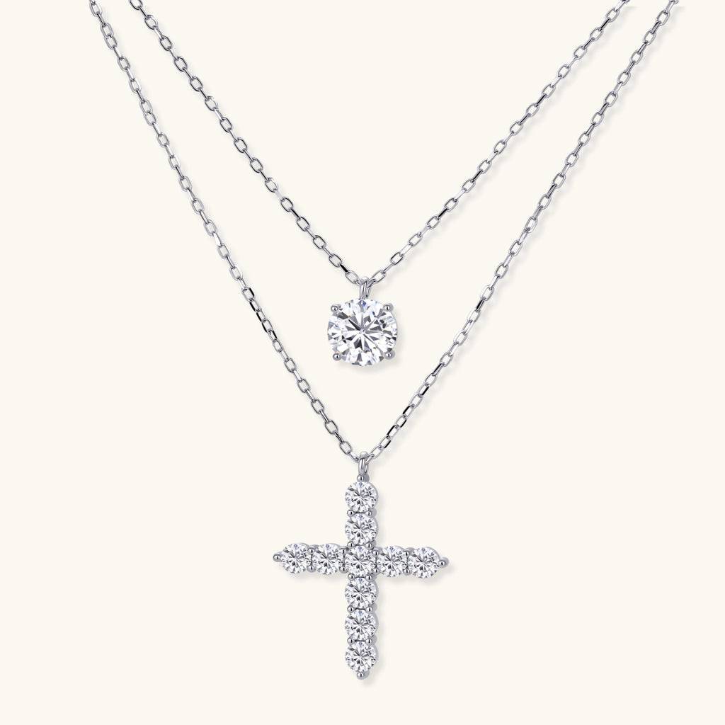 Two delicate sterling silver necklaces with moissanite stones - one solitaire pendant and one cross pendant on white background.