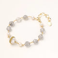 Bracelet with cloudy quartz beads, freshwater pearls, and gold-wrapped baroque pearl centerpiece on white background.
