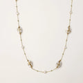 Long gold chain necklace with baroque pearls wrapped in leaf designs and small freshwater pearls spaced along the strand