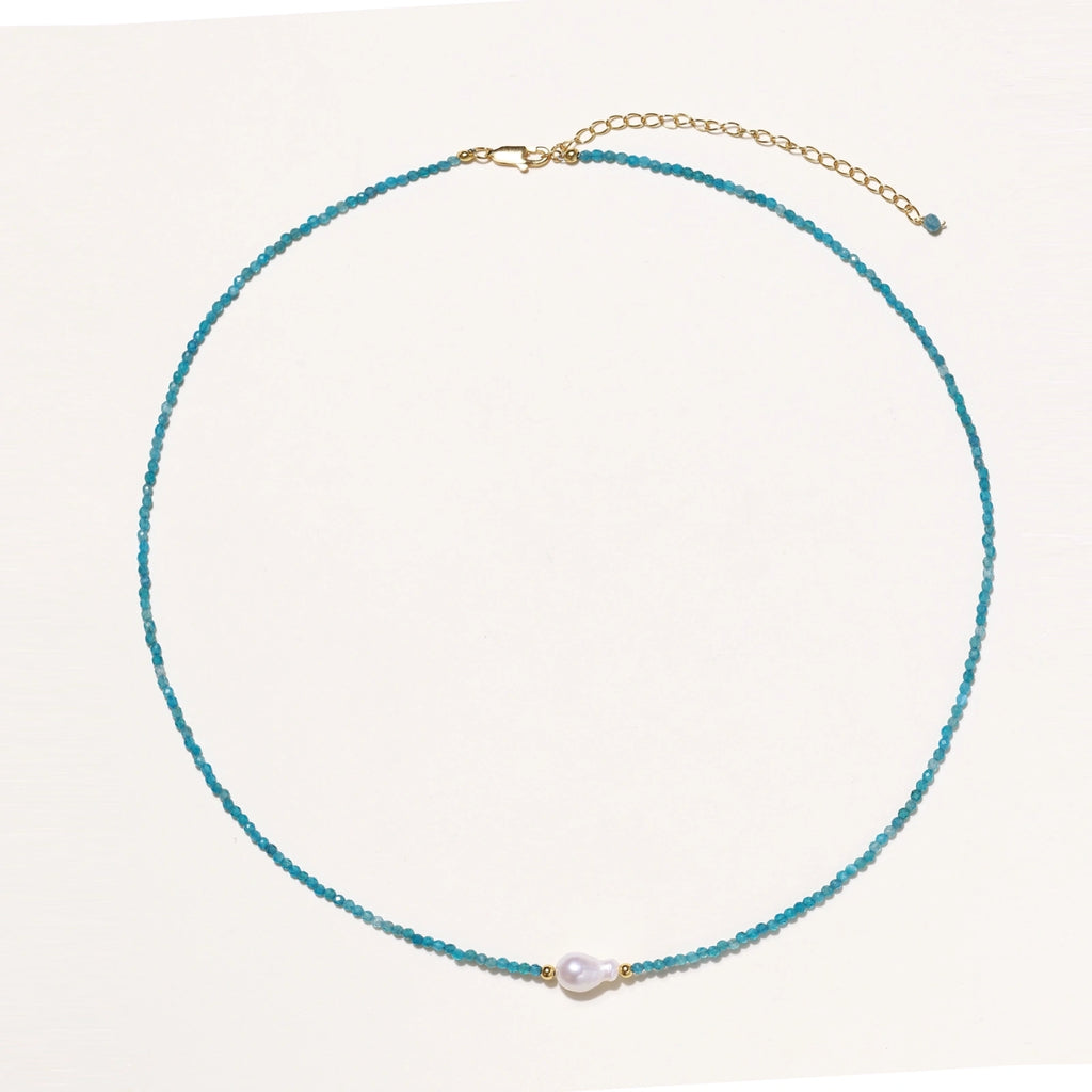 Delicate gold vermeil necklace with teal apatite beads and freshwater pearl on white background.
