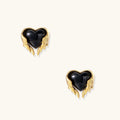 Glossy black heart-shaped studs with gold wing accents on cream background, gothic romantic style earrings