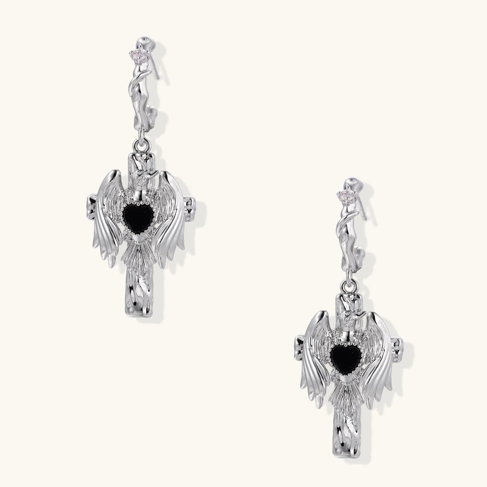 Silver drop earrings with twisted hoops and angel wings embracing black heart locket on white background.