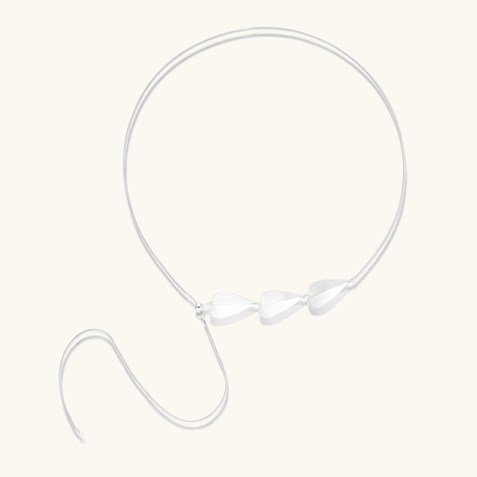 Minimalist sterling silver necklace with three brushed leaf-shaped pendants on delicate chain against white background