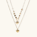 Three-layer 14K gold plated necklace with coin discs and dual heart pendants on cream background