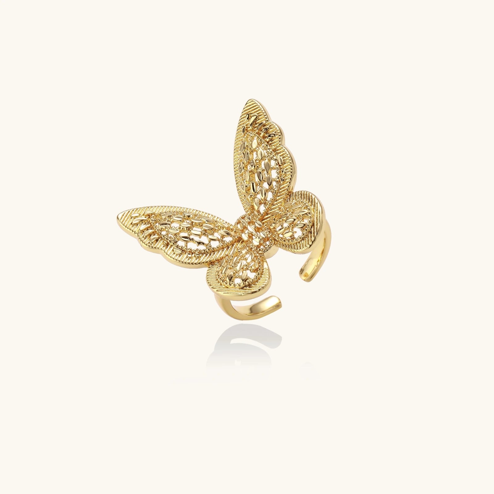 Intricate gold-plated butterfly ring with filigree cutout wings and adjustable band on white background.